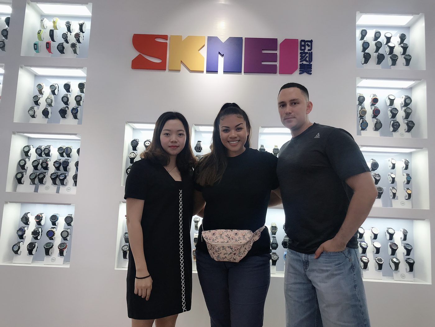 Overseas buyers with a SKMEI representative at the showroom logo wall, May 2019