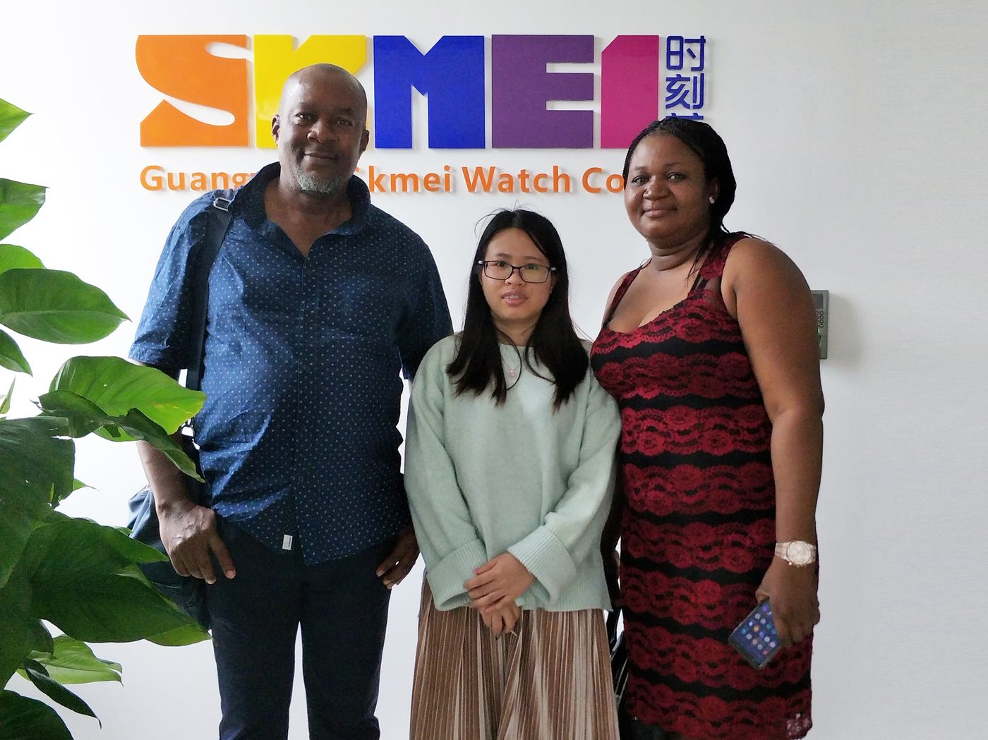 Overseas customers with a SKMEI representative at the company logo wall, 2019